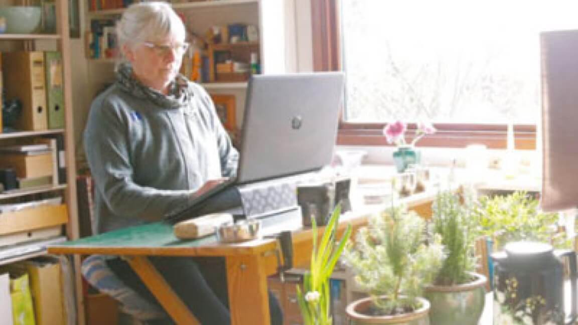 Svagsynet kvinde arbejder ved en computer i sit hjem