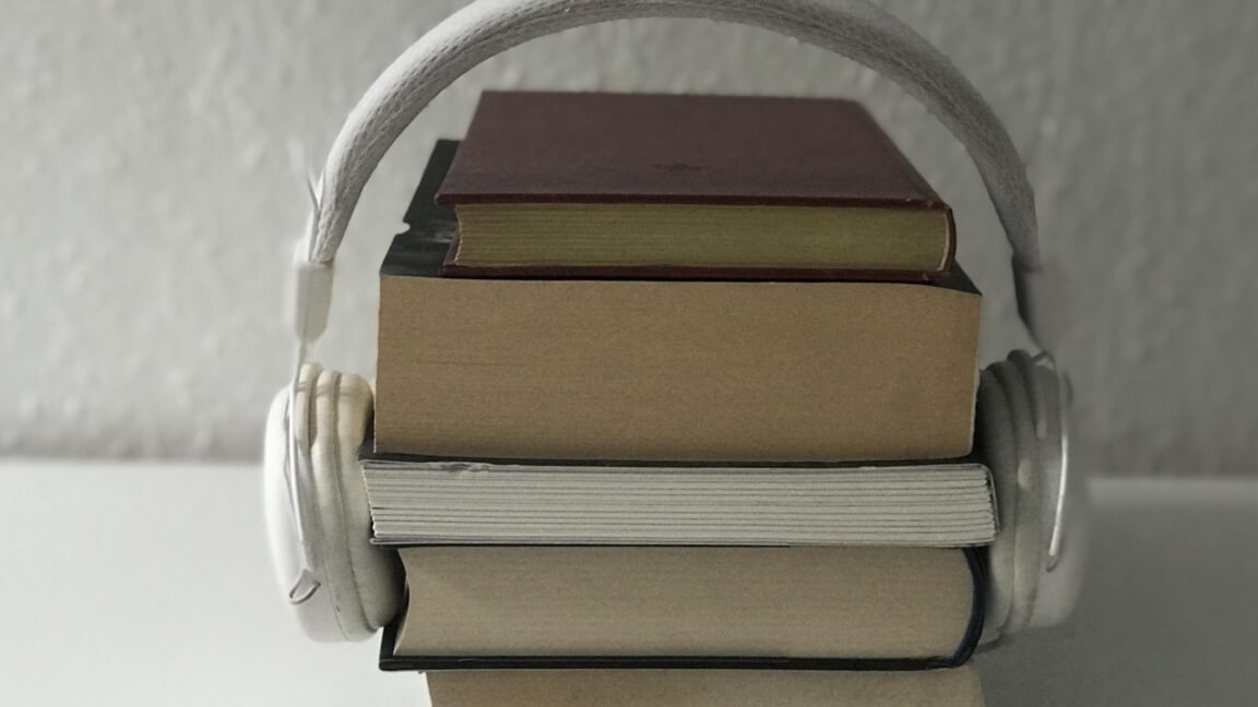 En stak bøger omsluttet af høretelefoner