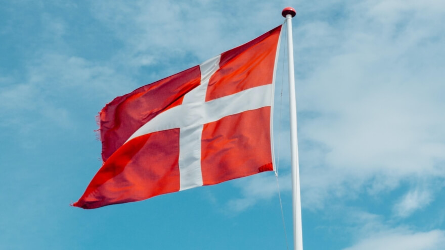 Dannebrog vajer på en blå himmel med skyer