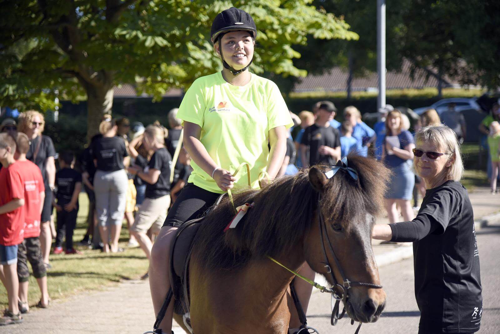 En elev er kommet højt til vejrs på en pony. I baggrunden er de andre elever ved at stille op til indmarch