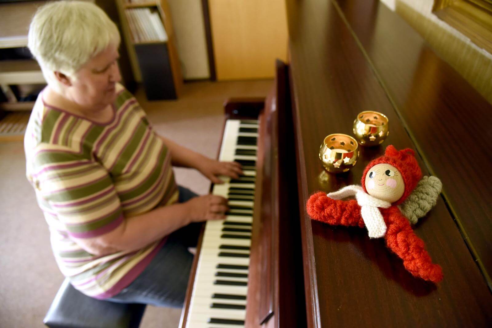 Anne spiller på klaver, hvor der i forgrunden står to guld fyrfarsstager og en strikket nisse