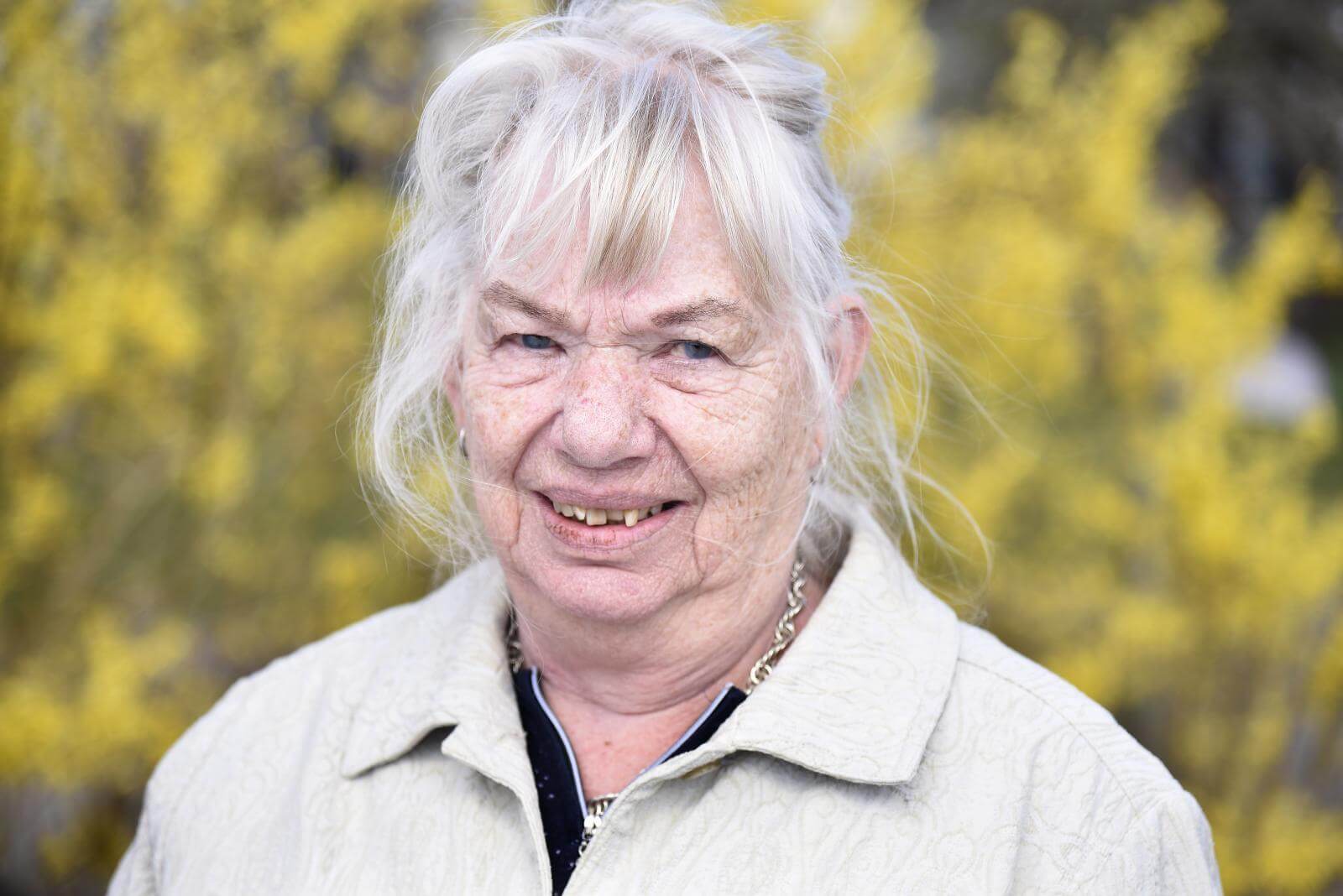 Portræt af Tove med gule forsythia blomster i baggrunden