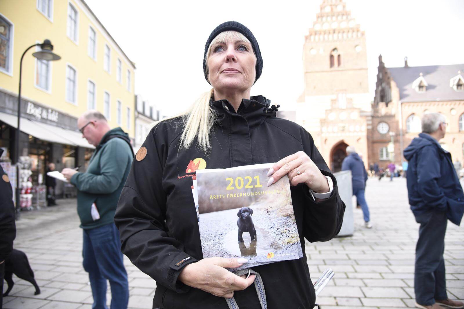 Førerhundekonsulent Tanja fremviser førerhundekalender 2021 med Roskilde domkirke i baggrunden