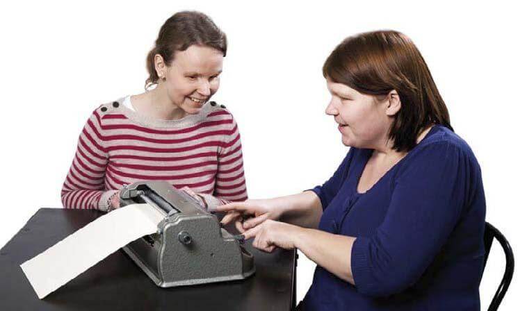 To blinde kvinder sidder ved en Perkins punktskrivemaskine
