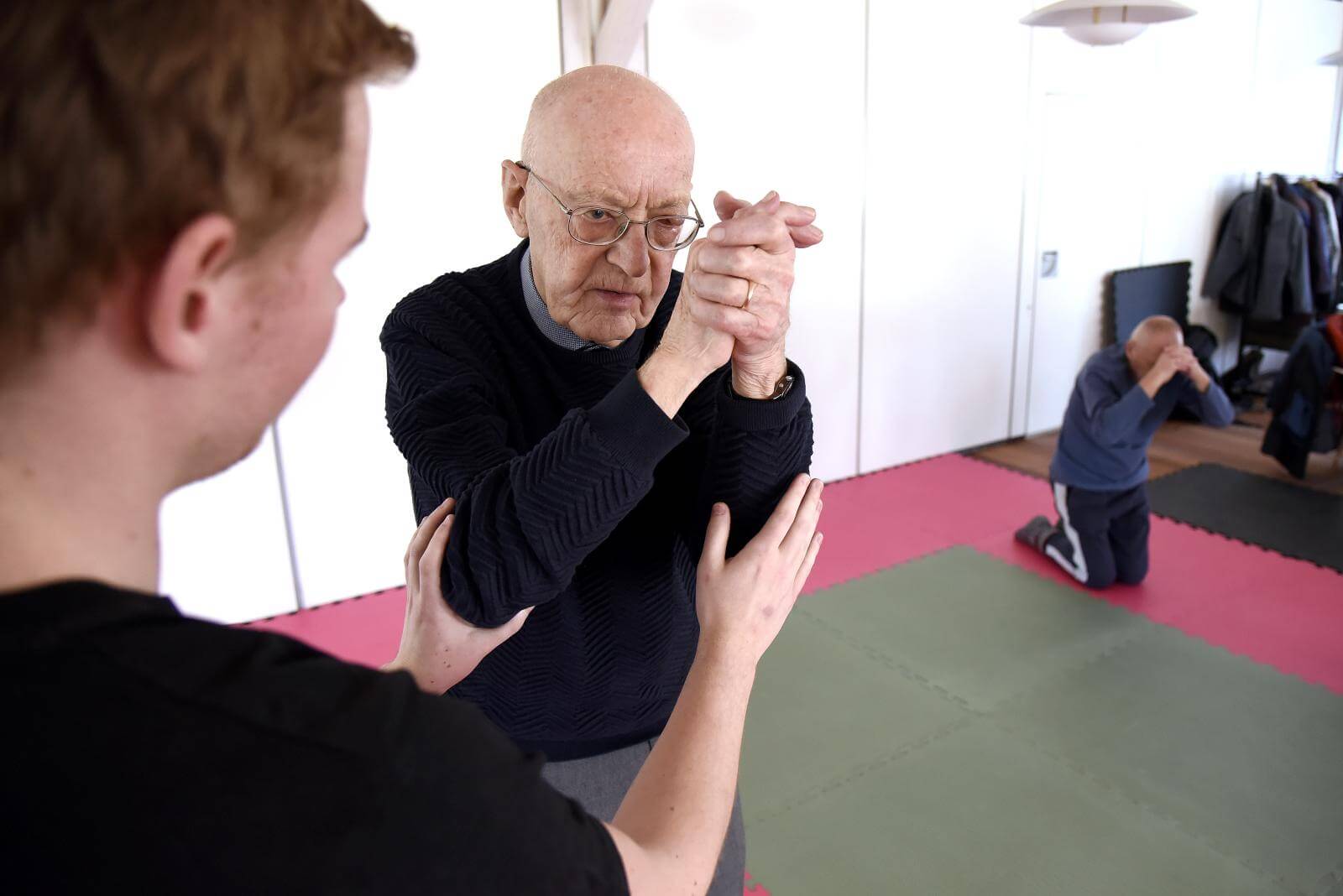 Ældre mandlig deltager får hjælp af undervise til at krydse armene foran hovedet
