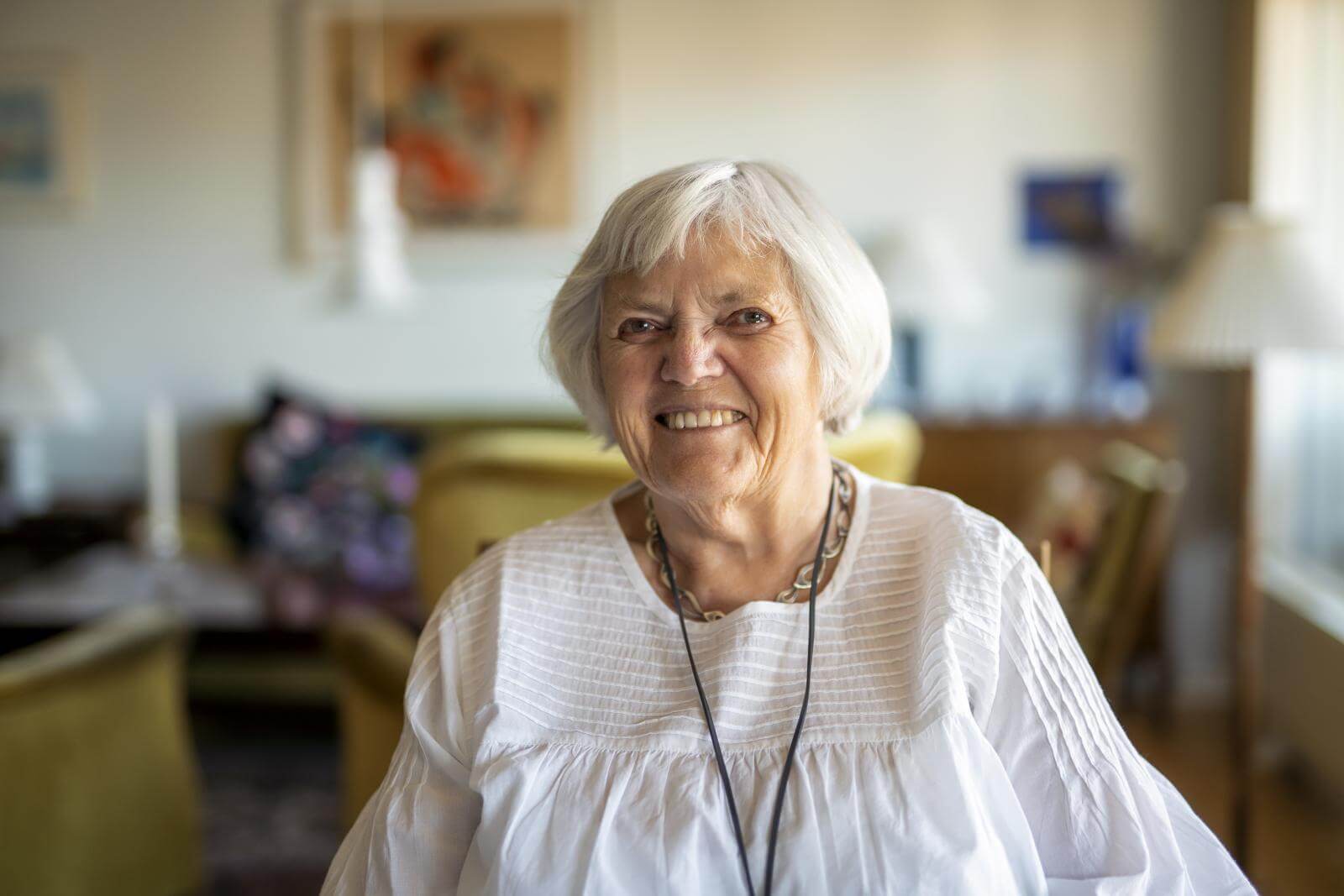 Portræt af smilende Hanne på 82 år ved spisebord