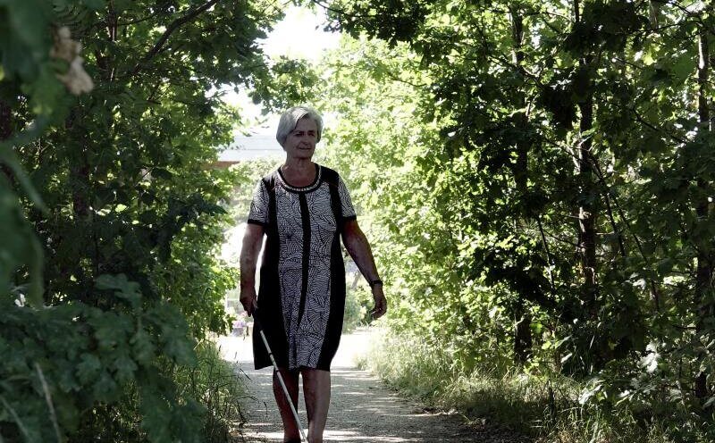 En kvinde går i en skov uden ledsager men med sin blindestok