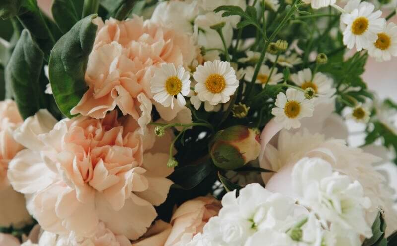 En buket blomster i hvide og sarte orange farver