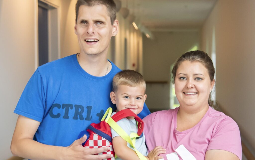 Forældre Thomas og Jeanette står på en gang med deres søn Mikkel i midten, der sidder på mors arm