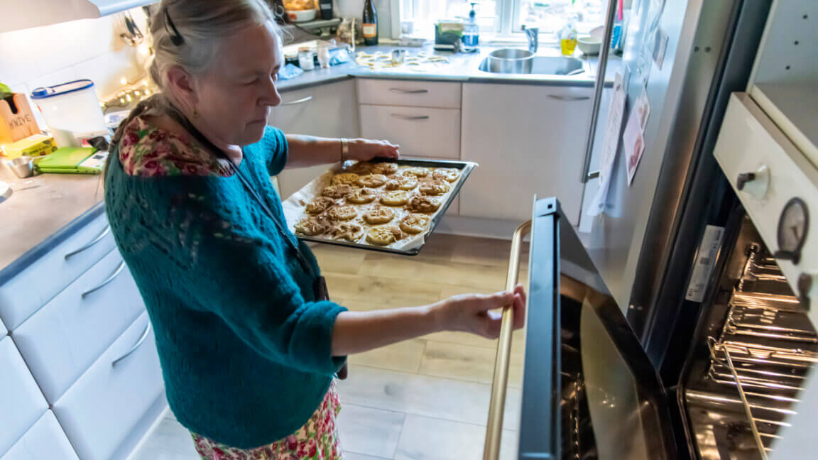 Mette sætter en bageplade i ovnen med småkager på