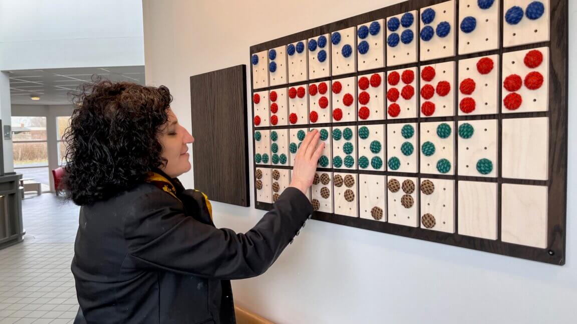En kvinde mærker på kunstværket, som forestiller punktskriftalfabetet af vævede prikker