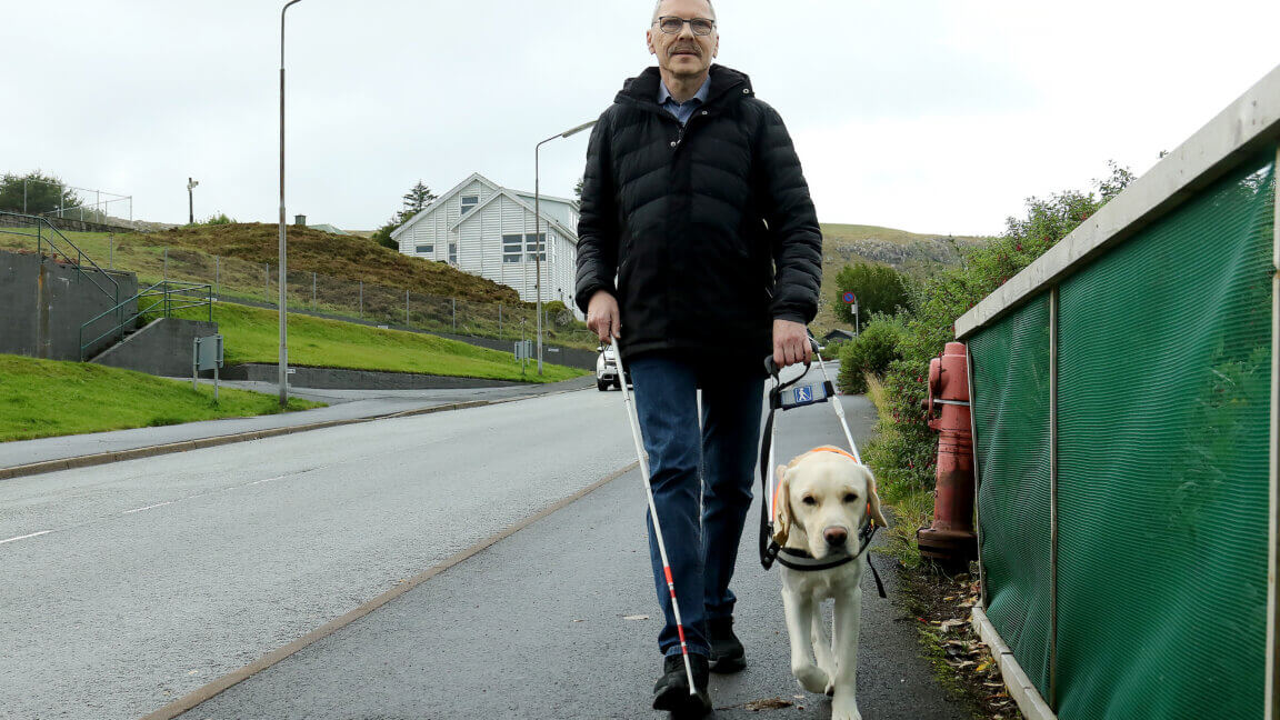 Johan går med førerhunden Milo på fortovet, en lys labrador