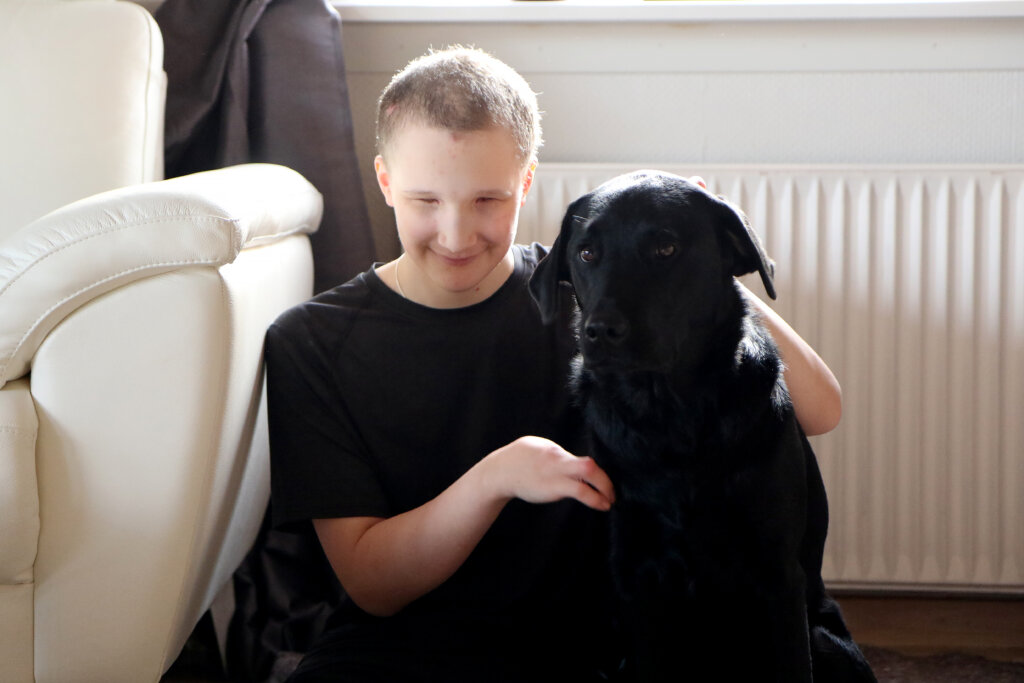 Andrias sidder på gulvet og klapper førerhunden Andy, en sort labrador