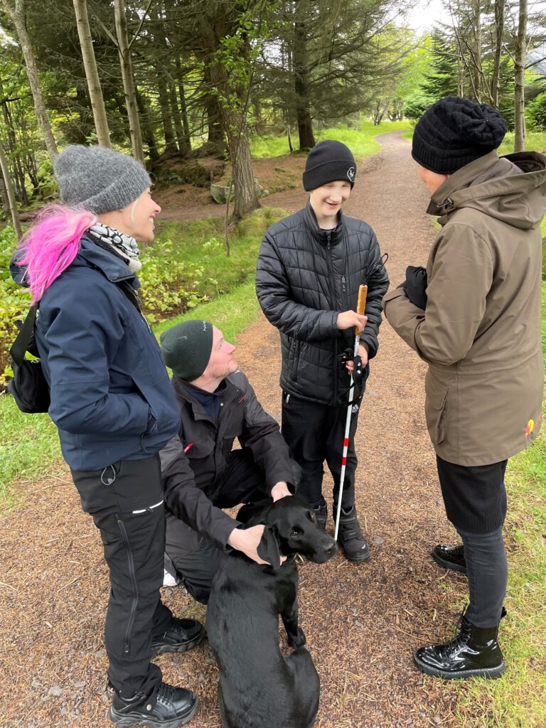 Andrias står med sin far, mor, førerhundeinstruktøren Tanja og førerhunden Andy, en sort labrador, i en park