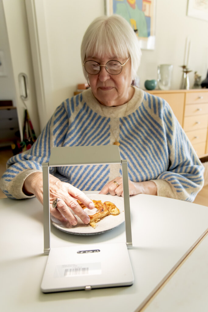 Birthe spiser et stykke kage med lys fra sin kuvertlampe