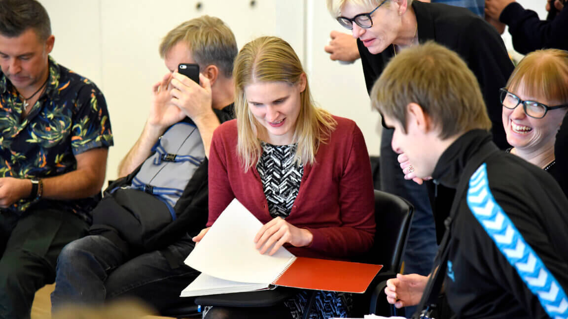 En gruppe mennesker på et tidligere kursus i jobkompasset sidder og kigger i materialet sammen