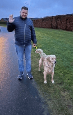 Michael går på en sti i skumringen med førerhunden Kesi ved sin side, en lys golden retriever