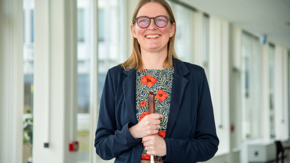 Diana står smilende med begge hænder om sin blindestok