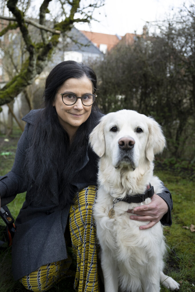 ¨Tijana sidder på hug uden for og holder en arm om førerhunden Buster, en lys golden retriever