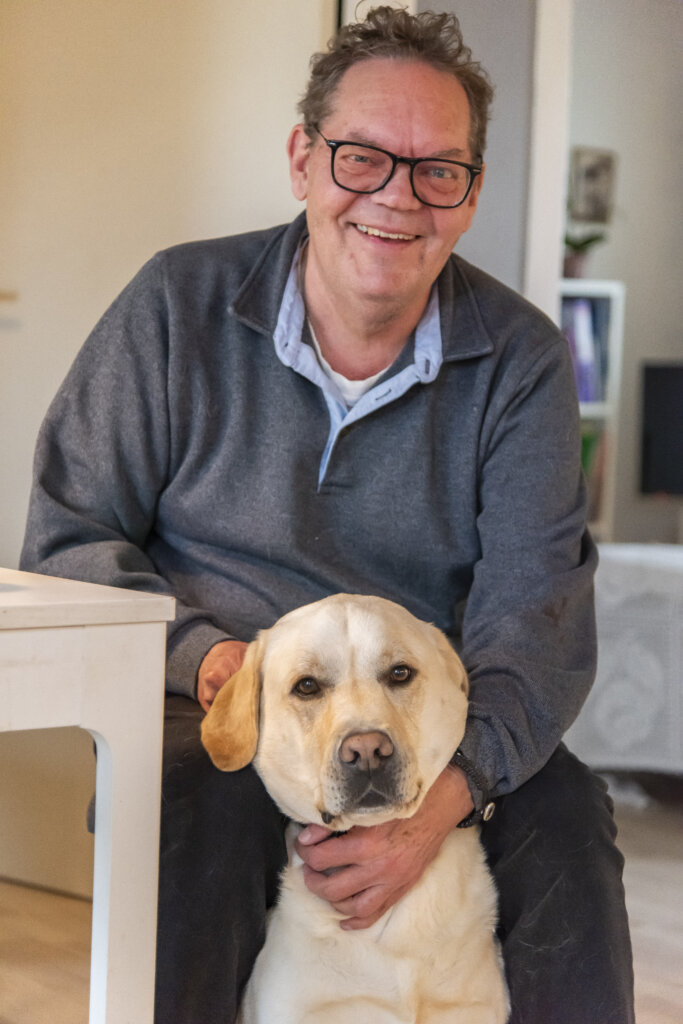 Finn sidder ved spisebord med Baloo mellem benene og aer ham
