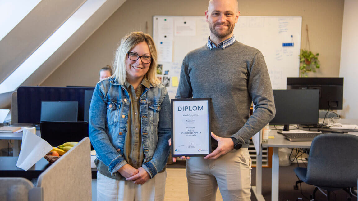 Kristoffer holder diplom for Årets Cphbusinesspraktik 2024/2025. Han står ved siden af sin praktikvejleder Marie på kontoret
