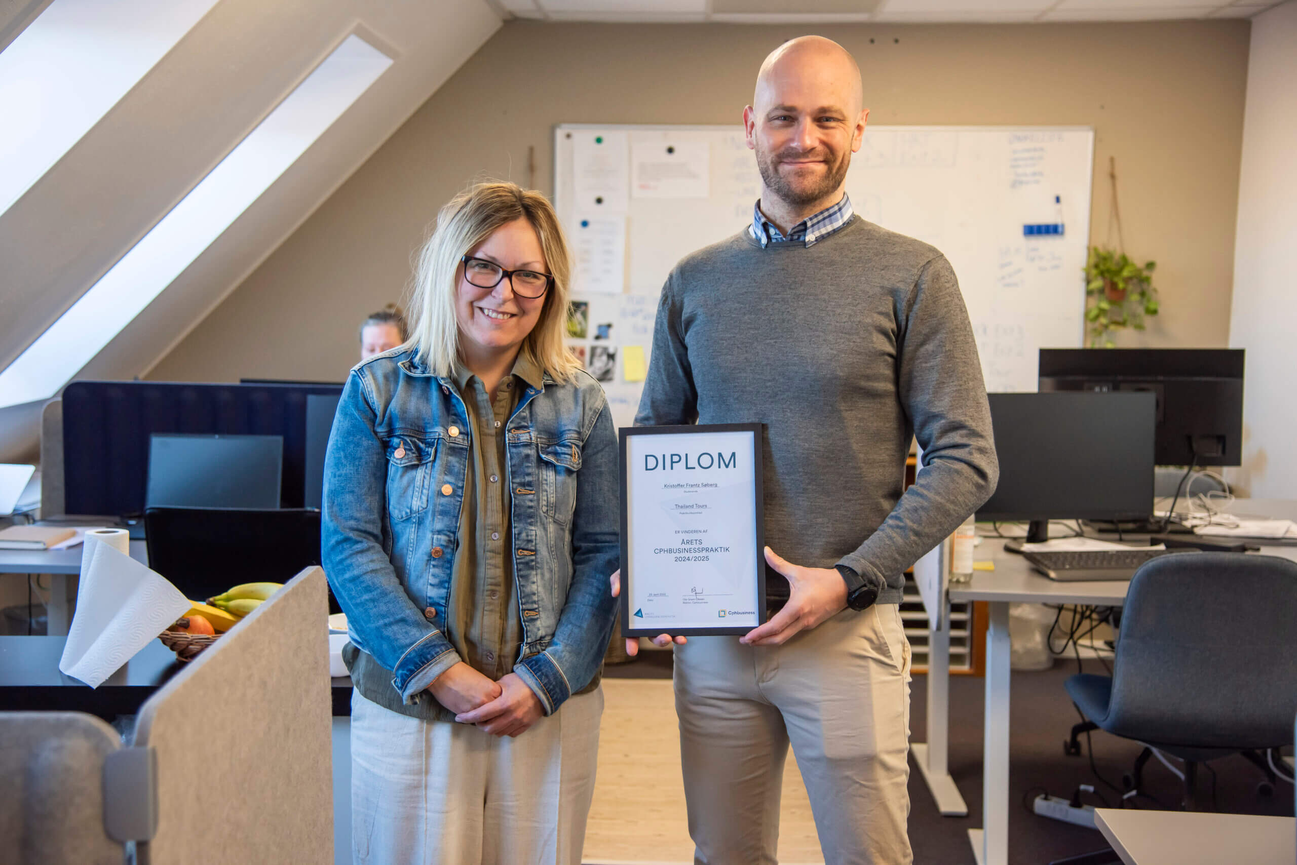 Kristoffer holder diplom for &Aring;rets Cphbusinesspraktik 2024/2025. Han st&aring;r ved siden af sin praktikvejleder Marie p&aring; kontoret
