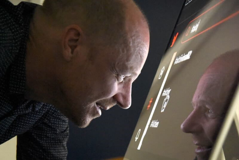 Karsten kigger helt tæt på computerskærmen. Han har skiftet farve på baggrunden, så den er sort med hvid tekst