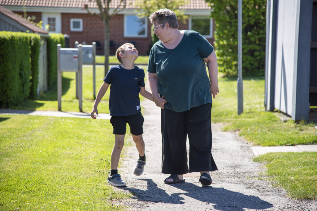 Marco hopper glad og holder sin mormor i h&aring;nden uden for. De griner til hinanden