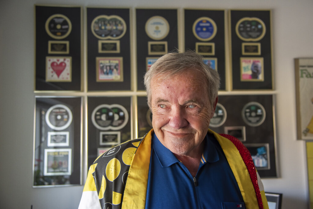 Lennart Johannesen er if&oslash;rt en spraglet jakke og smiler. Han st&aring;r foran sin samling af guldplader