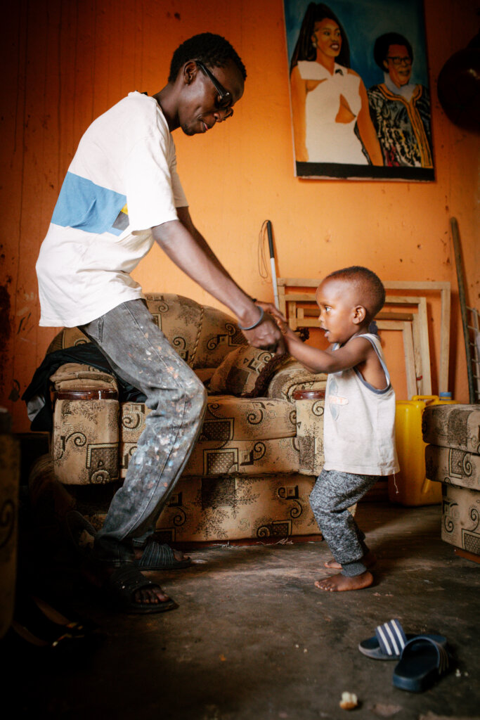 Jean de Dieu danser med sin 3-årige søn i stuen. De holder i hinandens hænder