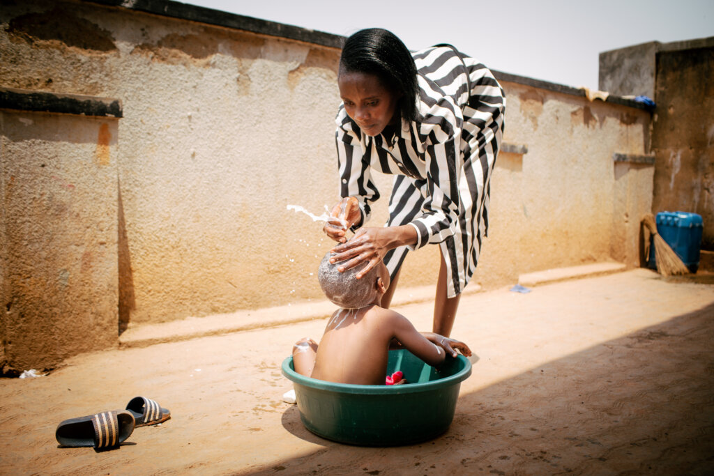 3-årige Kyrie vaskes af sin mor i en balje uden for