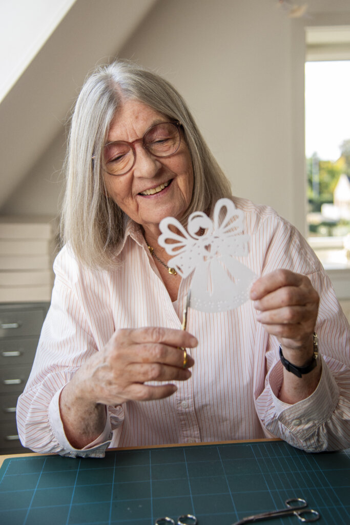 Portræt af Gitte, som klipper juleenglen af papir med en fin lille guldsaks