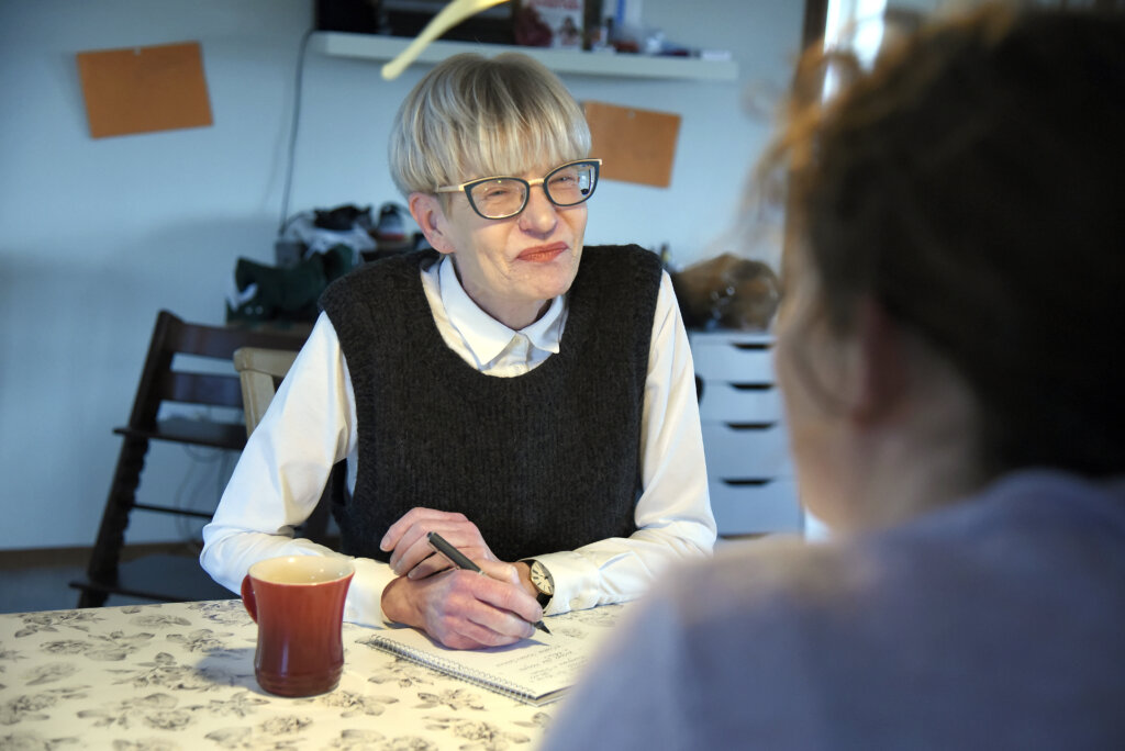 Helle sidder ved et bord over for et medlem og noterer p&aring; sin blok