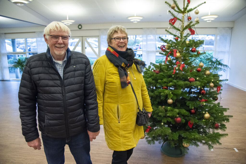 Billedet viser Grethe og Peter der står og holder i hånd. Ved siden af dem står et juletræ.