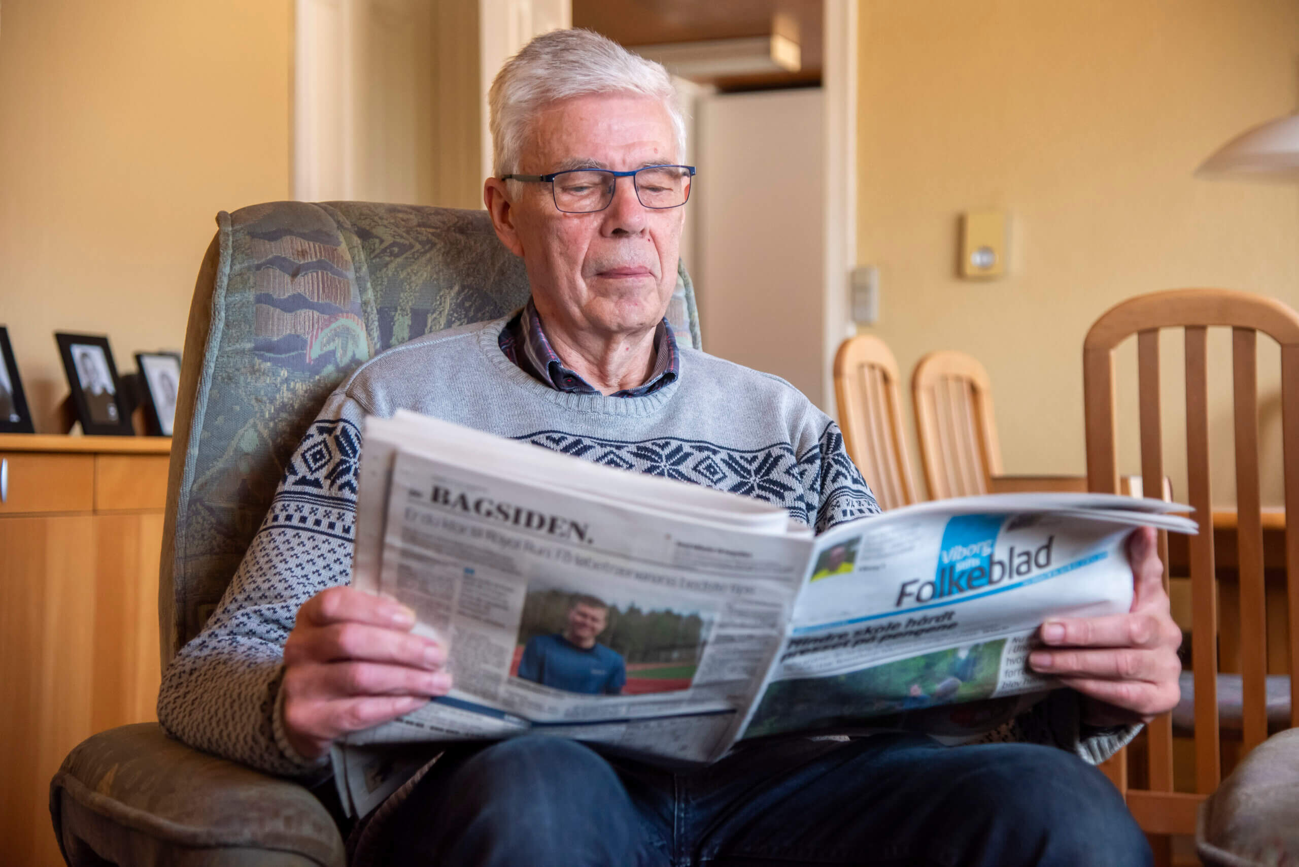 Orla l&aelig;ser avis i sin l&aelig;nestol i stuen