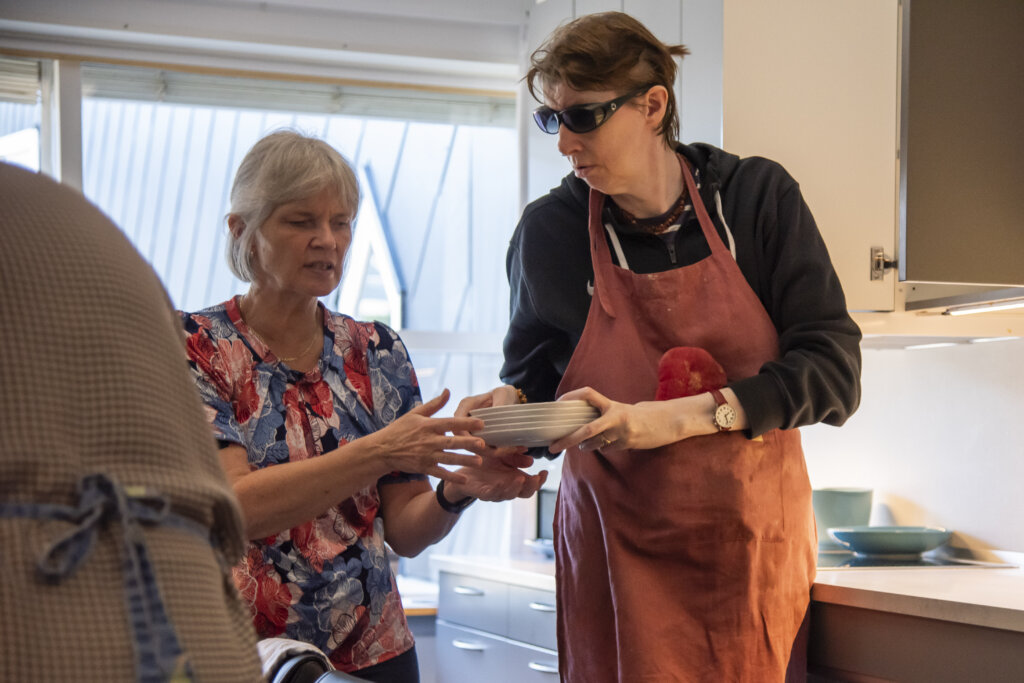 Berit rækker tallerkener til Anette, som stiller dem på bordet