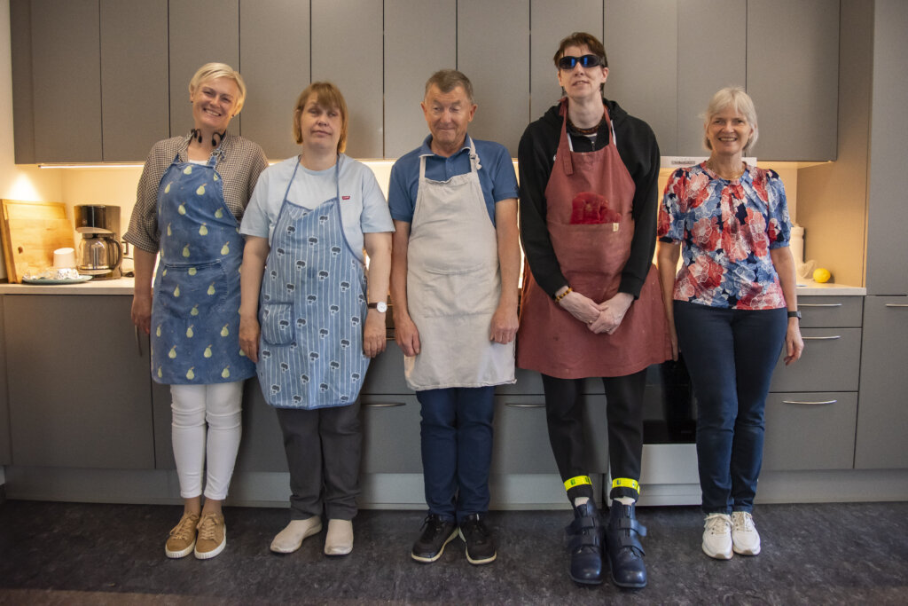 Gruppebillede af tre kursister og to undervisere på madlavningskursus. De står foran kursuskøkkenet på Fuglsangcentret