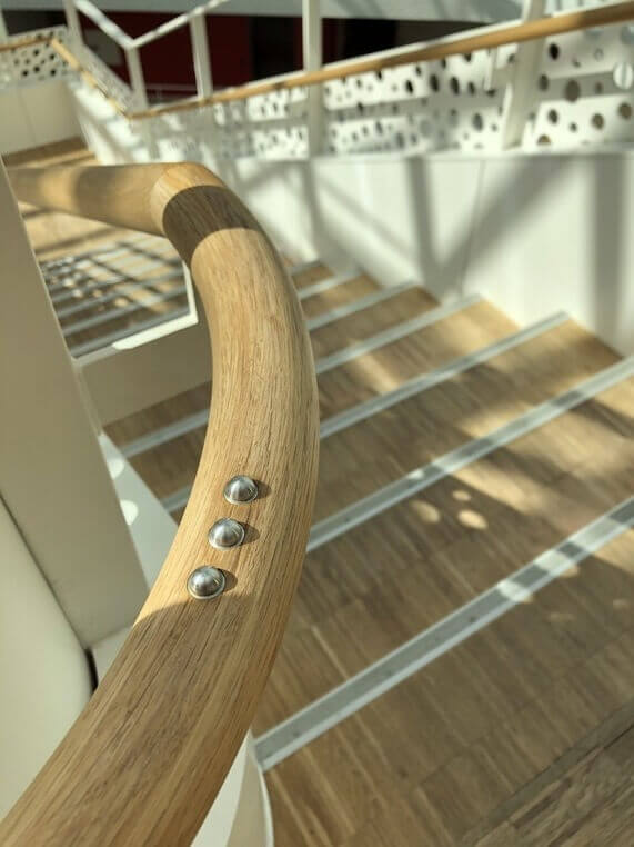 N&aelig;rbillede af trappe med tr&aelig;h&aring;ndliste og tydelige kontrastmarkeringer p&aring; trinfladerne, der forbedrer sikkerhed og orientering.