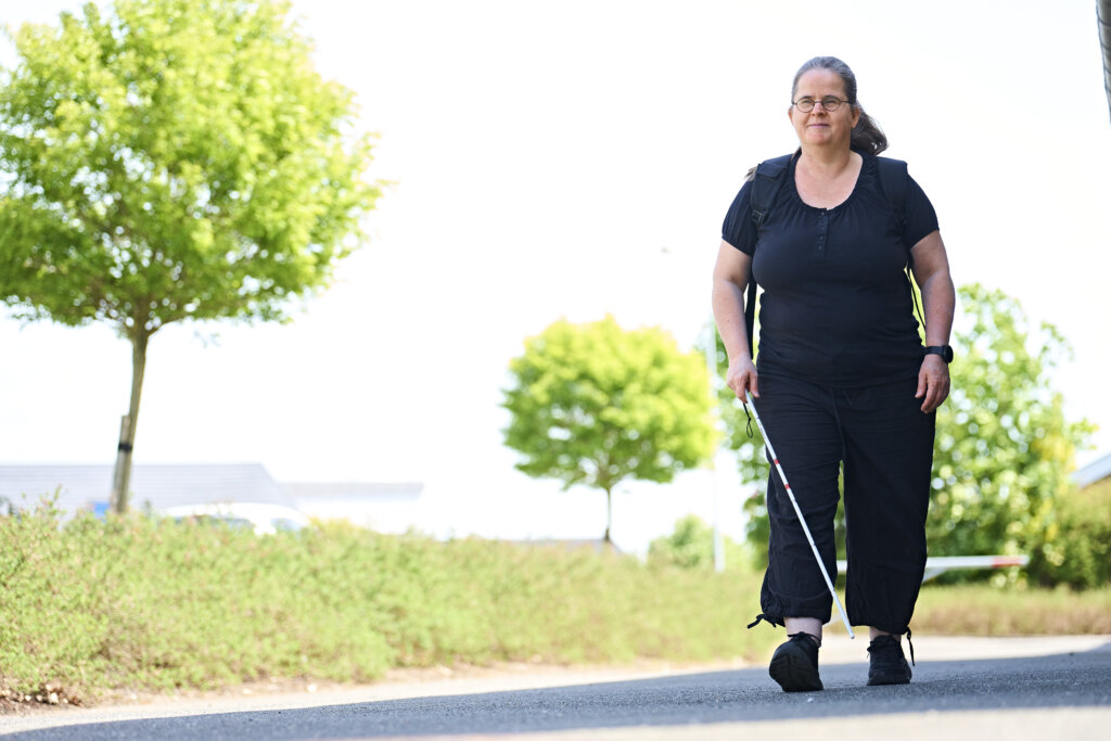 Karina kommer gående uden for med sin blindestok