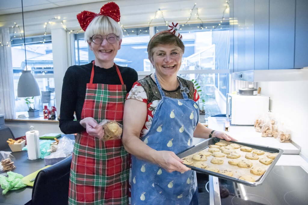 Jannie og Helle holder en plade med småkager på. De har begge forklæder på og julepynt i håret