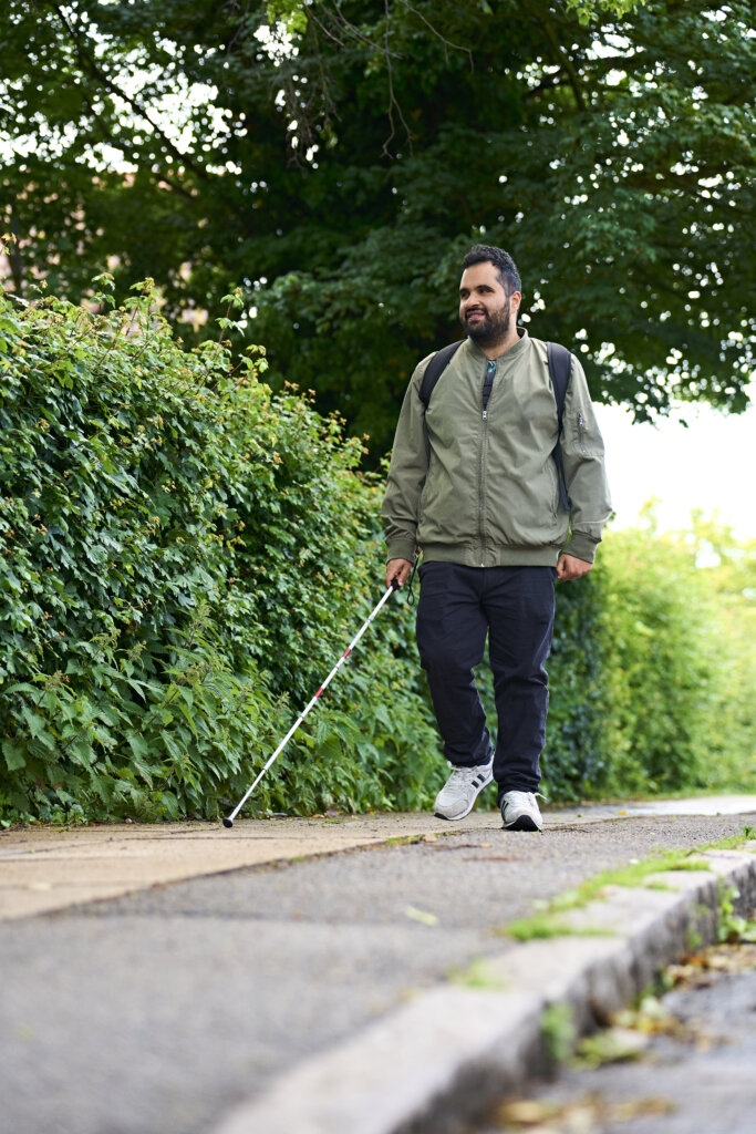 Mohammed kommer gående på fortovet med sin blindestok
