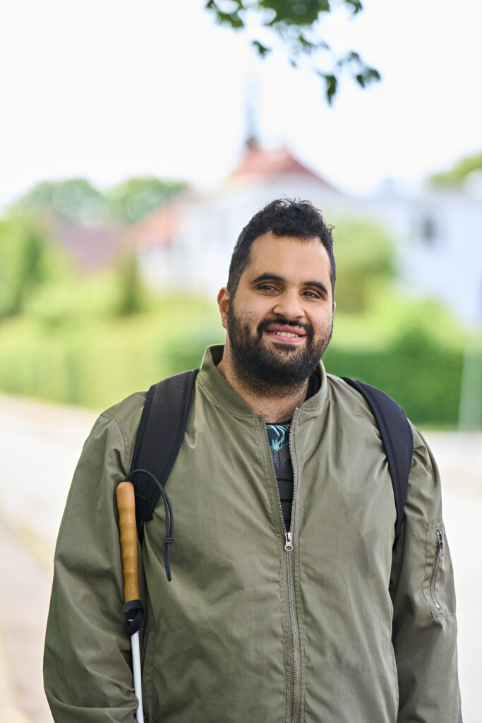 Portræt af smilende Mohammed uden for, som står med sin blindestok 