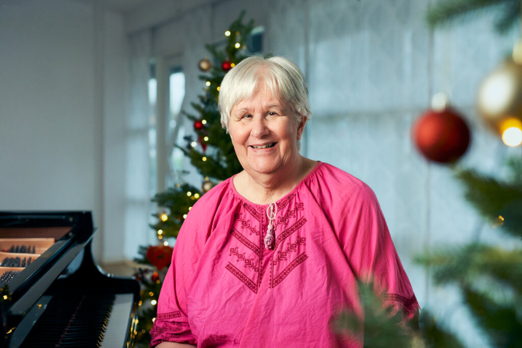 Anne sidder foran flyglet p&aring; FSC. I baggrunden st&aring;r et juletr&aelig; med lys og kugler