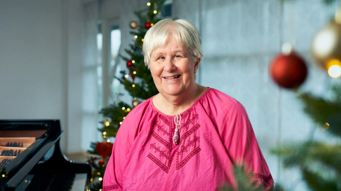 Anne sidder foran flyglet på FSC. I baggrunden står et juletræ med lys og kugler