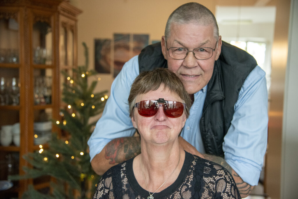 Olga sidder, mens Peter st&aring;r bagved. Der er et juletr&aelig; i baggrunden