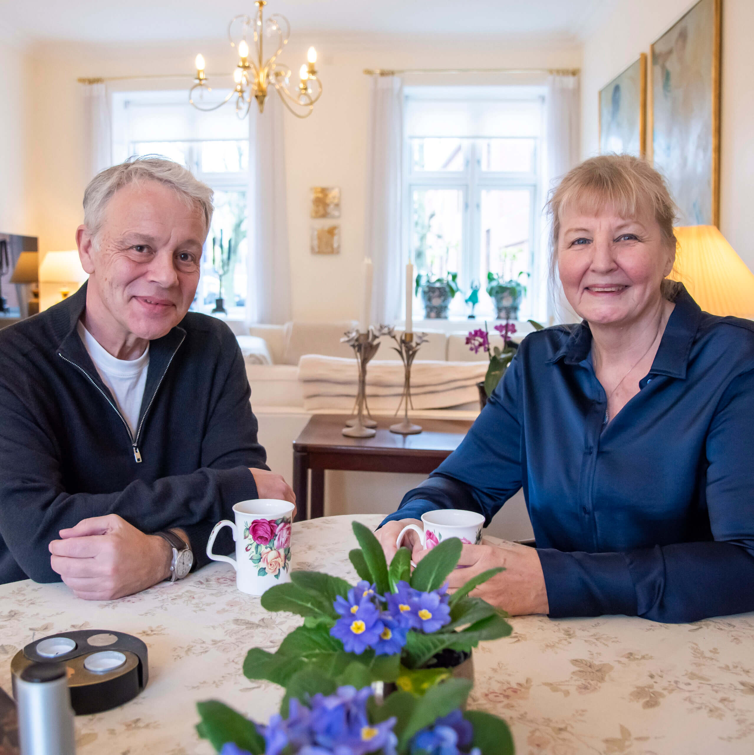 Ægteparret Helle og Henrik sidder ved spisebordet og drikker kaffe