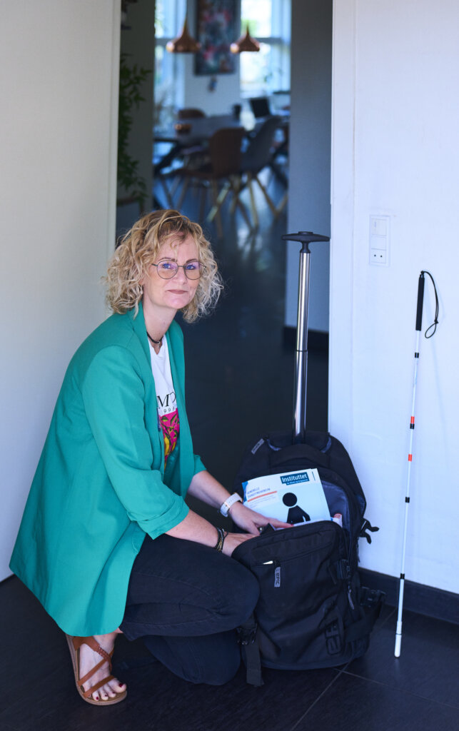 Rikke sidder p&aring; hug og er ved at pakke sin taske med hj&aelig;lpemidler, hun medbringer til hjemmebes&oslash;g