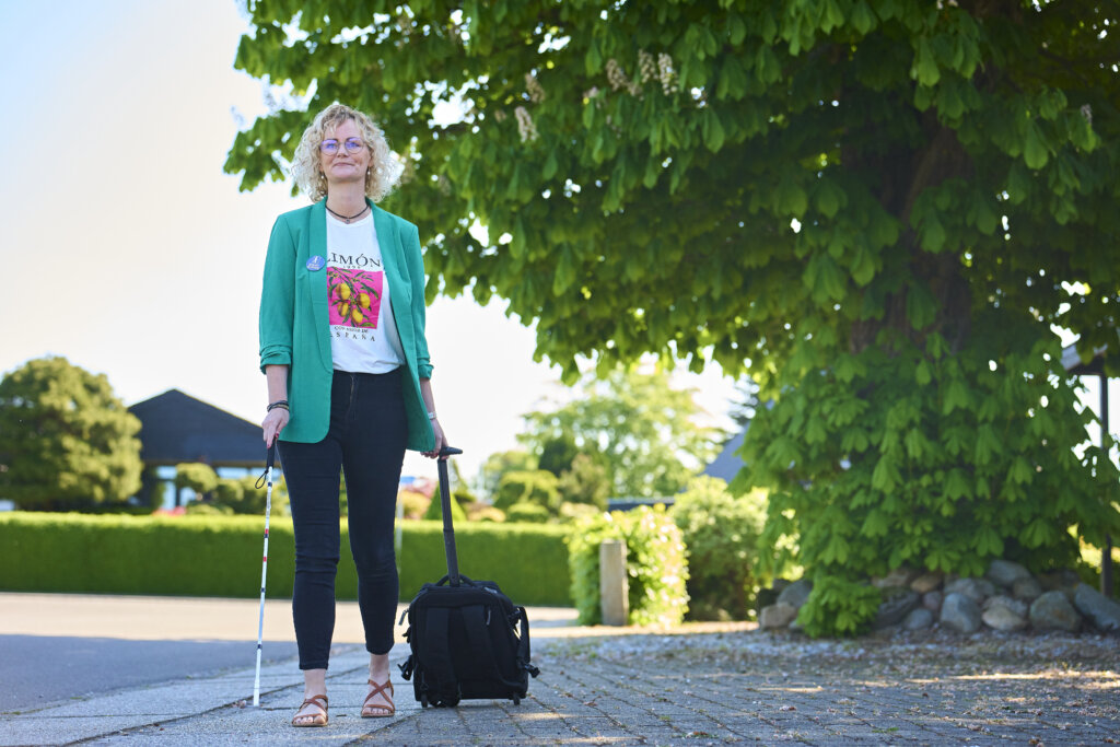 Rikke kommer g&aring;ende uden for med sin rullende kuffert