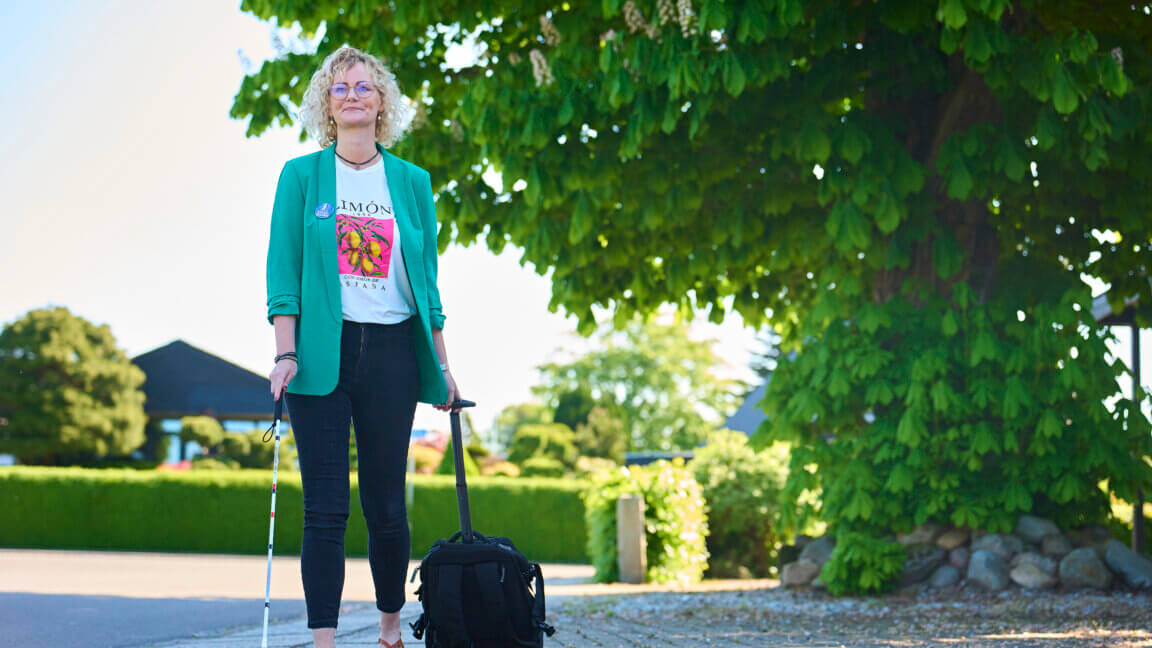 Rikke kommer gående uden for med sin rullende kuffert