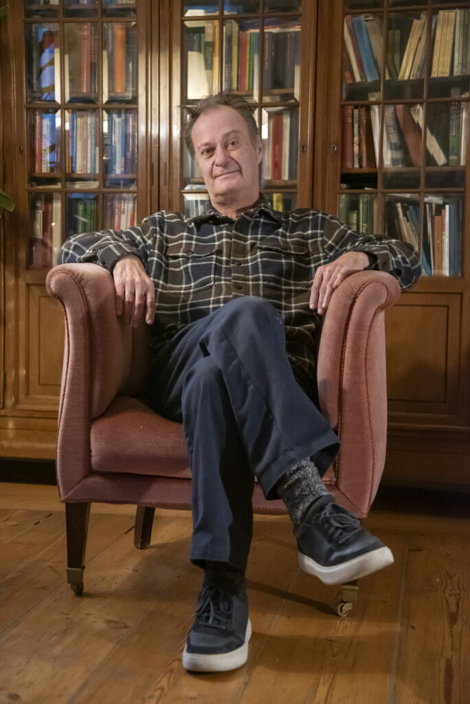 Knud Romer sidder i sin l&aelig;nestol foran et fyldt bogskab